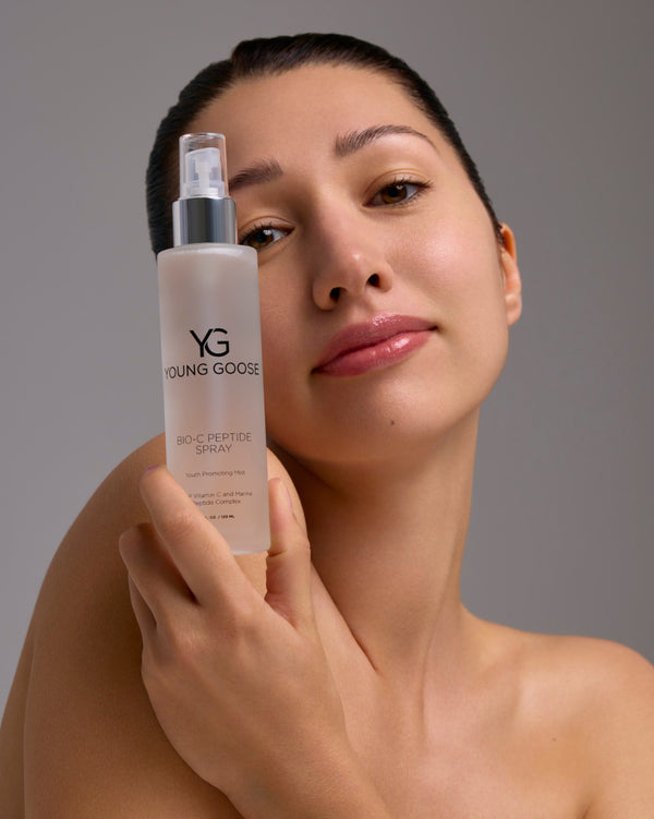 A woman holding a full size bottle of Young Goose Bio-C Peptide Spray