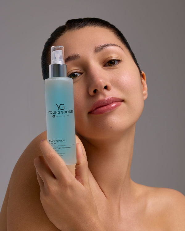Woman holding a bottle of Young Goose Blue Peptide Spray