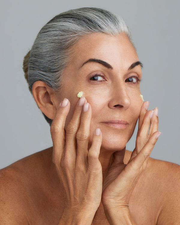 An older woman applying a Young Goose C.A.R.E. (CARE) Anti-Aging Moisturizer 