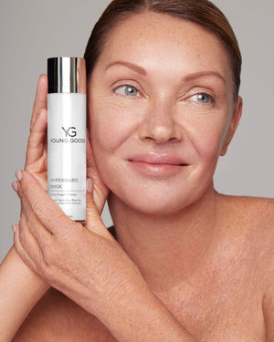 Woman holding a full size bottle of Young Goose Hyperbaric Mask near her face