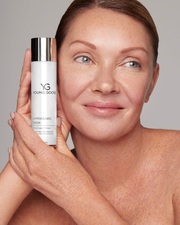 Woman holding a full size bottle of Young Goose Hyperbaric Mask near her face