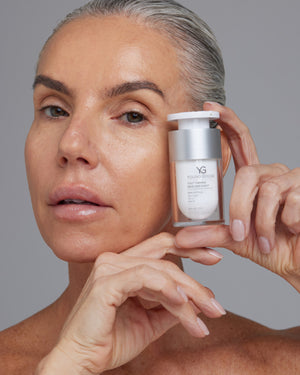 Model holding a travel size of Young Goose Youth Firming Neck and Chest Cream #15ml